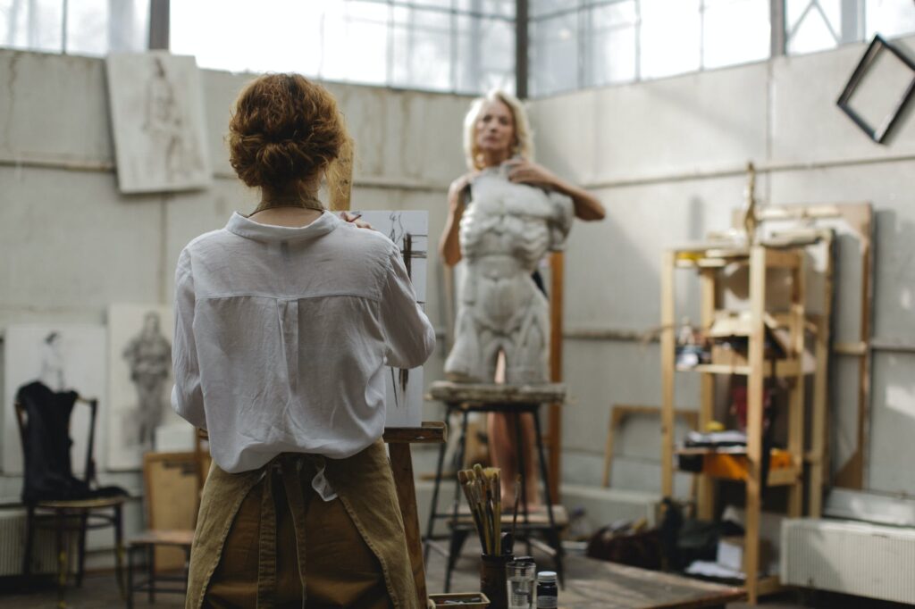 an artist painting a model holding a sculpture