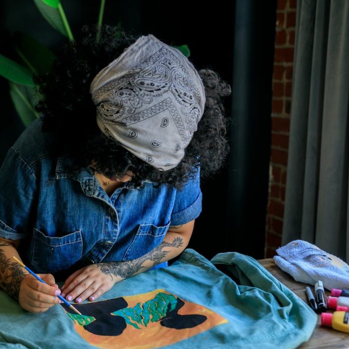 woman concentrated on painting on the jeans shirt