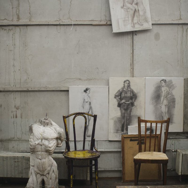 white concrete statue near brown wooden chairs